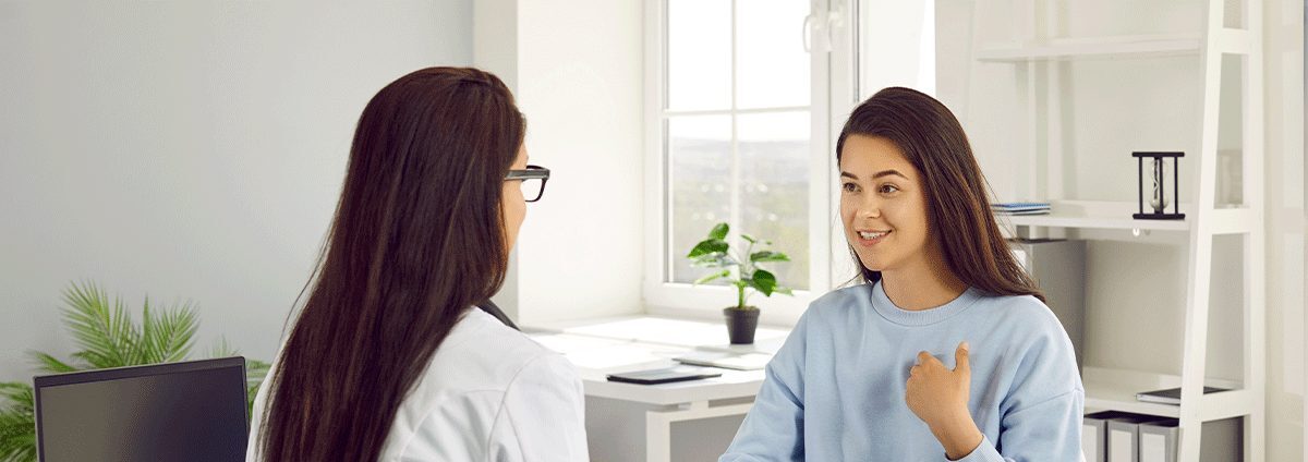 Young woman speaking with a female counselor during a supportive one-on-one consultation in a bright office setting, reflecting emotional support and healing after a difficult experience